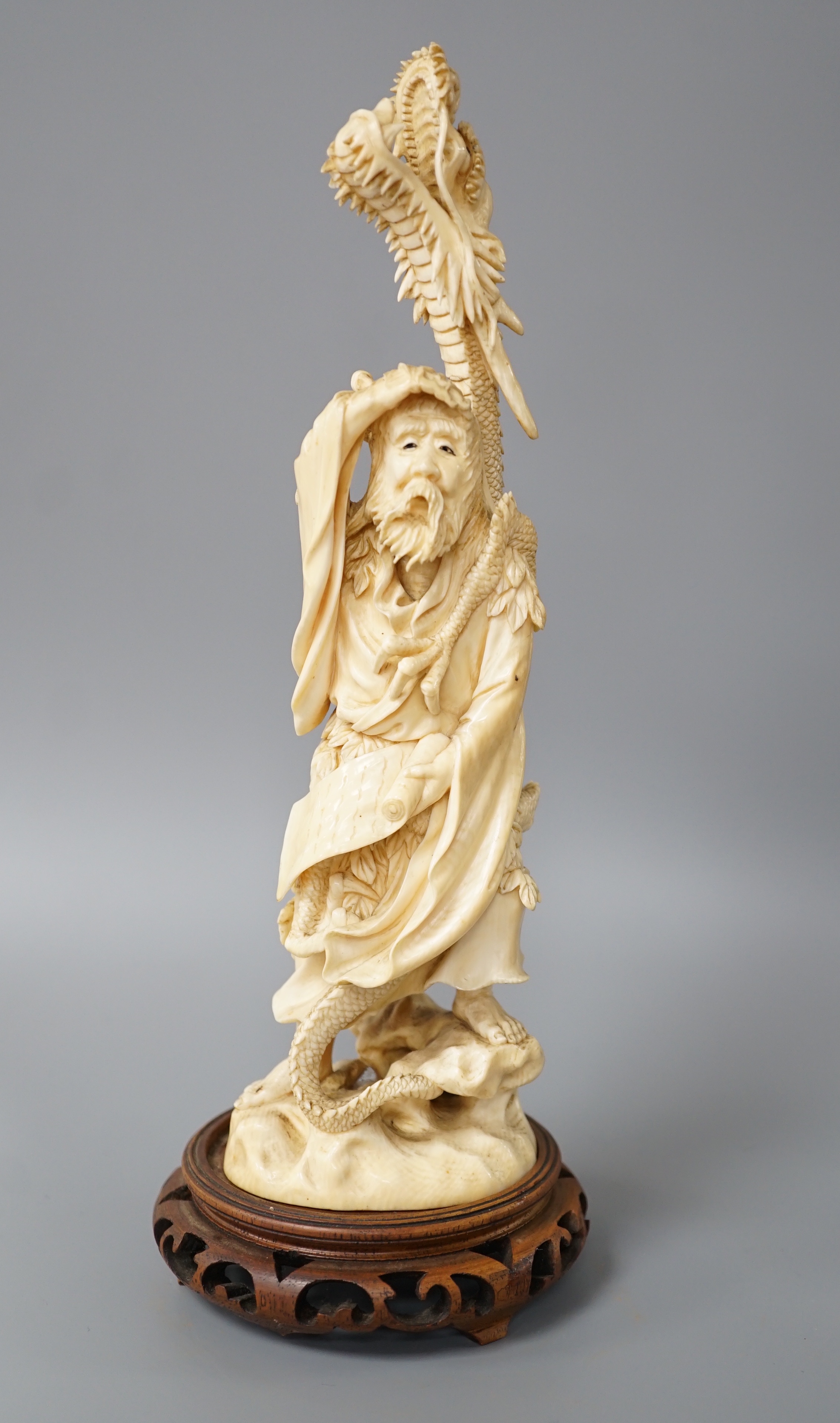 A Japanese ivory okimono of Shoshi Sennin and a dragon, early 20th century, signed, associated wood stand, 24cm excl stand